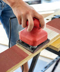 Person using red palm sander with 1/4 Sheet Sandpaper Pack 4.5 By 5.5 Inches P60 Red Aluminum Oxide Plain Backing 50 Sheets for DIY woodworking