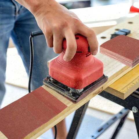 Person using red palm sander with 1/4 Sheet Sandpaper Pack 4.5 By 5.5 Inches P60 Red Aluminum Oxide Plain Backing 50 Sheets for DIY woodworking