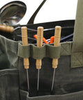 Close-up of army green Waxed Canvas Firewood Carrier Tote For Camping And Garden Work with tools in pockets