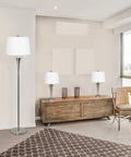 Tapered 3 Lamp Set With White Fabric Shades In Brushed Nickel, Includes 2 Table Lamps And 1 Floor Lamp, Great For Living Room, Bedroom, Foyer Or Home Office Lighting in an elegant setting.