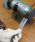 User holding a metal tool near a 6 inch bench grinder equipped with Premium Nylon Deburring Wheels 6 Inch, 180 Grit Silicon Carbide Buffing Pads 5 Pack.