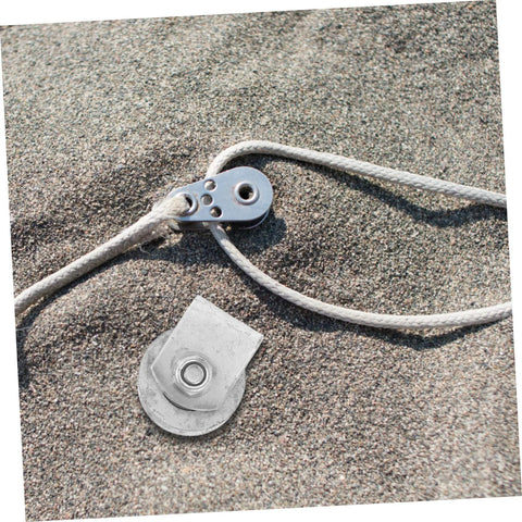 Close-up of cast-iron V-groove wheel pulley with rope and mounting plate on sand