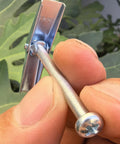 Close-up of hand holding a 1/4x3 inch carbon steel toggle bolt with spring wing, part of a pack of 50 for hollow wall surfaces.