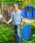 Man using Rain Barrel Spigot Kit For Water Barrels PVC 3/4 Inch Spigot With Bulkhead Fitting Hose Adapter to water garden