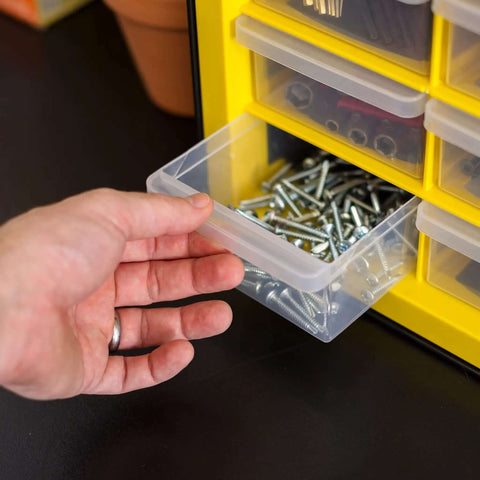 Person retrieving a clear drawer filled with screws from the Totally Rad Plastic Hardware Organizer With Forty Four Drawers.