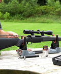Person using Compact Range Vise with Folding Forks and NonMarring Cradle for Easy Transport and Safe Firearm Cleaning outdoors.