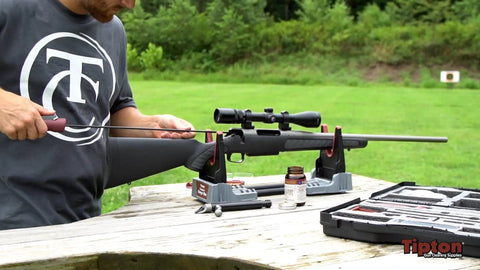 Person using Compact Range Vise with Folding Forks and NonMarring Cradle for Easy Transport and Safe Firearm Cleaning outdoors.
