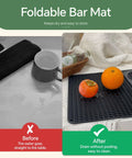 Front view of black foldable bar mat on countertop; 18×12 in drying surface for barware, with oranges.