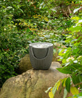 Outdoor Tabletop Water Fountain With LED Lights Made From Recycled Polyethylene Eco Friendly Materials For Patio Porch And Backyard Bubbling Water Feature UV Resistant Durable Yard Decor For All Weather placed on a rock in a garden setting.