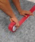 Person using Underlayment Seam Tape 100 Feet Red For Floating Floors PVC Based Moisture Resistant Easy Tear Seams Bonding for Carpet Padding