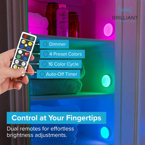 Remote controlling Wireless RGB LED Puck Lights Kit With Remotes For Under Cabinet Shelves And Walls Battery Operated Color Changing And Fade Modes 55 Lumens Per Light Easy Adhesive Or Screw Mount 6 Pack in a colorful cabinet display.