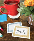 Classroom Cottage Name Tags And Labels Multi Pack For Teachers with pens, coffee mug, and flowers on wooden desk