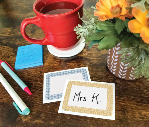 Classroom Cottage Name Tags And Labels Multi Pack For Teachers with pens, coffee mug, and flowers on wooden desk