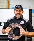 Copper-nickel brake line tubing coil held by a mechanic in a workshop.