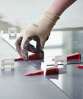 Hand using Perfect Level Master Anti Lippage Tile Leveling System Kit with 500 self-leveling clips for flush tile installation.