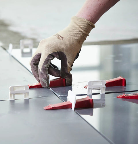 Hand using Perfect Level Master Anti Lippage Tile Leveling System Kit with 500 self-leveling clips for flush tile installation.