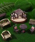 Ten Piece Fairy Garden Furniture Set Resin Miniatures With Hand Painted Tables Chairs And Benches For Village Homes Micro Landscape Decoration DIY Craft Gifts displayed with moss backdrop.