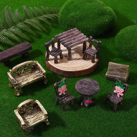 Ten Piece Fairy Garden Furniture Set Resin Miniatures With Hand Painted Tables Chairs And Benches For Village Homes Micro Landscape Decoration DIY Craft Gifts displayed with moss backdrop.