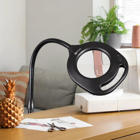 Two In One ClearSun LED Magnifier Light Floor And Table Lamp for crafting and sewing on a wooden desk next to sewing materials