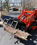 Compact 460 Mini Skid Steer Loader With Front Loader And Hydraulic Grapple Bucket Attachments holding a log on a driveway.