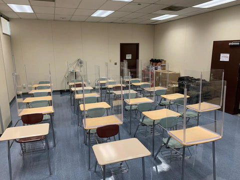 Classroom with individual desks equipped with clear acrylic dividers for safety, promoting social distancing during lessons.