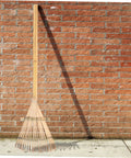 Portable Garden Hand Rake With Wear Resistant Tines leaning against brick wall
