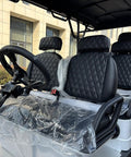 Interior of Six Seater Electric Leisure Cart With Premium Upholstered Interior, featuring quilted black seats and steering wheel.