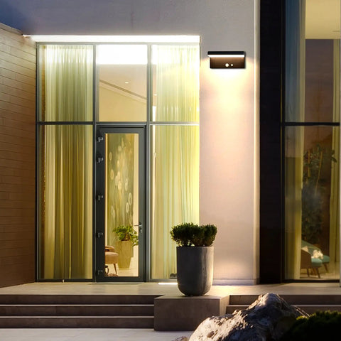 Solar Motion Sensor Outdoor Wall Light With 600 Lumen Output And 3 Modes mounted by entrance at night, IP44 aluminum, no wiring