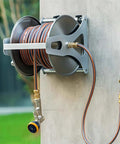 Heavy Duty Stainless Steel Garden Hose Reel Trolley With Easy Spin Crank, wall-mounted with hose and spray nozzle visible.