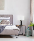 D'Alessio Table Lamp In Matte Black With Modern Cutout Body And White Linen Shade, 20 Inch Tall in a stylish bedroom setting