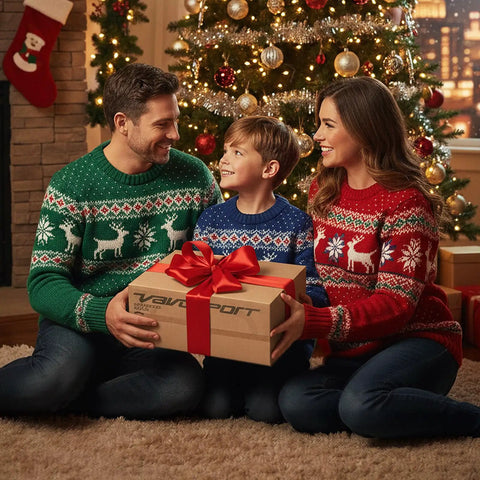 Family in festive sweaters sitting by a Christmas tree holding a gift box with a red ribbon, holiday decorations in background.