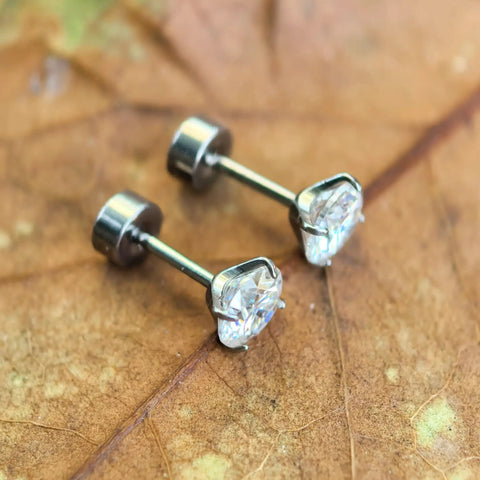 Premium D Color Moissanite Stud Earrings Crafted From Certified G23 Implant Grade Titanium Screw Back on leaf background.