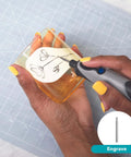 Dremel Stylo+ Craft Rotary Tool Kit with 15 accessories; gray handheld engraver with blue button engraving a glass jar