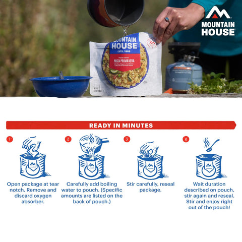 Pouring water into a Mountain House freeze-dried meal for quick outdoor preparation, outdoor setting in the background.
