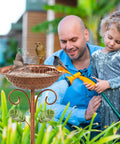 Father and daughter using hose near Vintage Copper Metal Bird Bath Stand for Outdoors with birds in garden setting.