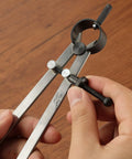 Professional All Metal Drafting Compass With Lockable Slider And Pencil Holder in hand, showing lock slider and pencil holder details.