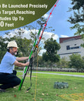 Man using Arborist Slingshot Throw Line Rope Launcher With Trigger For Adults in a park, aiming at tree branches.