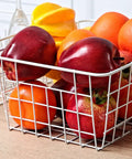 Set Of 4 White Wire Storage Baskets For Freezer, Pantry, And Bathroom Organization filled with assorted fruits