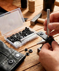12 Piece Leather Snap Fasteners Kit Built Tough 15Mm Brass Snap Buttons Press Studs With Setting Tools Rivets and Snaps For DIY Crafts and Clothing Black, person using setting tool on leather in workshop.