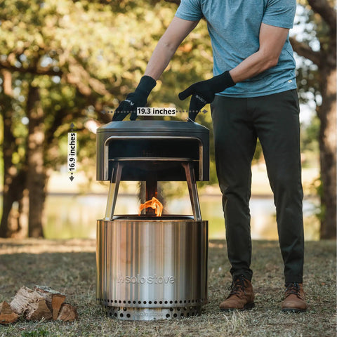 Person setting up Bonfire Pi Fire Pizza Oven Accessory on fire pit with Cordierite Stone, demonstrating wood burning assembly.