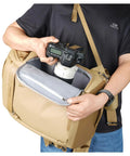 Person accessing camera in Metro B30L 30L Camera Backpack With Convertible Daypack In Beige, Fits 70 To 200mm Lens Attached