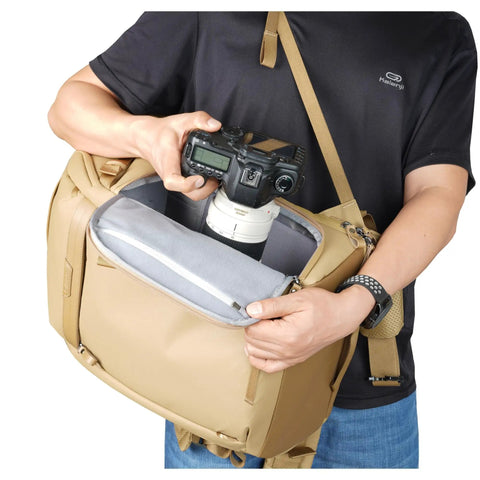 Person accessing camera in Metro B30L 30L Camera Backpack With Convertible Daypack In Beige, Fits 70 To 200mm Lens Attached
