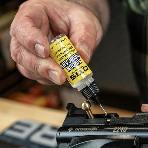 Applying silicone lubricant from airgun maintenance kit to airgun component, enhancing peak performance of rifles and pistols.