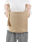 Person holding Dope Natural Rope Woven Storage Basket With Wooden Bead Handles Macrame Organizer For Blankets, Toys, Clothes, Shoes And Plants Indoor Home Decor Bin In Brown 28x28 Cm.
