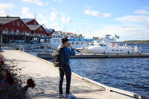 Person using 30L Camera Backpack For Photography And Video Gear With Full Front Panel Access Ultra Comfortable Dual Density Straps at harbor