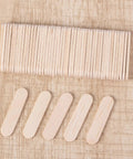 Top Shelf Food Safe Mini Popsicle Sticks For Crafting Great Treats Natural Untreated Wood Popsicle Poles laid out on a textured background.