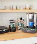 Slim Under-Counter Coffee Pod Drawer For 24 K-Cups shown holding pods under a coffee maker on a kitchen counter
