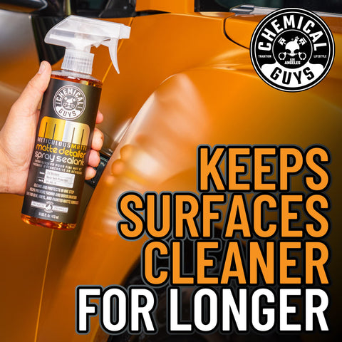 Meticulous Matte Finish Detailer and Spray Sealant for Satin and Matte Surfaces Quick Detailer That Keeps the Non Gloss Look Safe on Vinyl Wraps for Cars Trucks and SUVs 16 Oz bottle held by a hand in front of a car's matte surface.