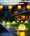 Epic Yard Glow Solar Globe Garden Lights 80 LED Cracked Glass Outdoor Ground Path Lights Waterproof 5.9ft 2 Pack Warm White glowing on a rainy night by a modern house patio.