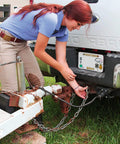 User attaching a 4 Pack 5/16 Inch Grade 70 Clevis Slip Hooks With Safety Latches Built Like A Tank Forged Steel Rigging to a trailer.